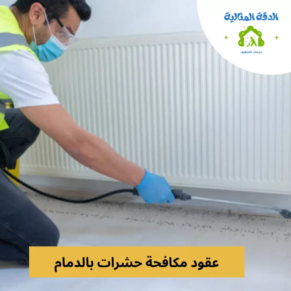 فني يرتدي قفازات وكمامة يقوم برش المبيدات على الأرضية بالقرب من حائط لمكافحة الحشرات في الدمام.